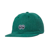 Green cap with the “Krooked” logo embroidered on denim hat