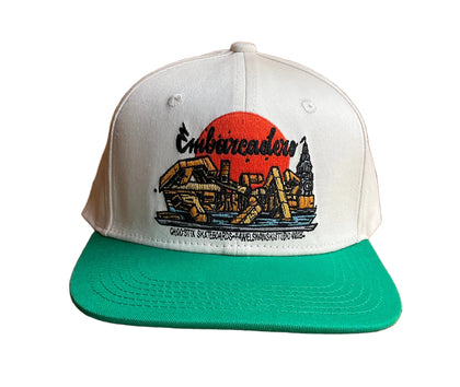 A two-tone snapback cap with a white crown and a bright green flat brim, featuring a EMB fountain graphic on the front with the text 'Embarcadero' and a red sun illustration.