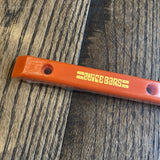 Orange OJ Juice Bar Rail skateboard rail, with yellow "JUICE BARS" logo, wrapped in plastic on a wooden surface.